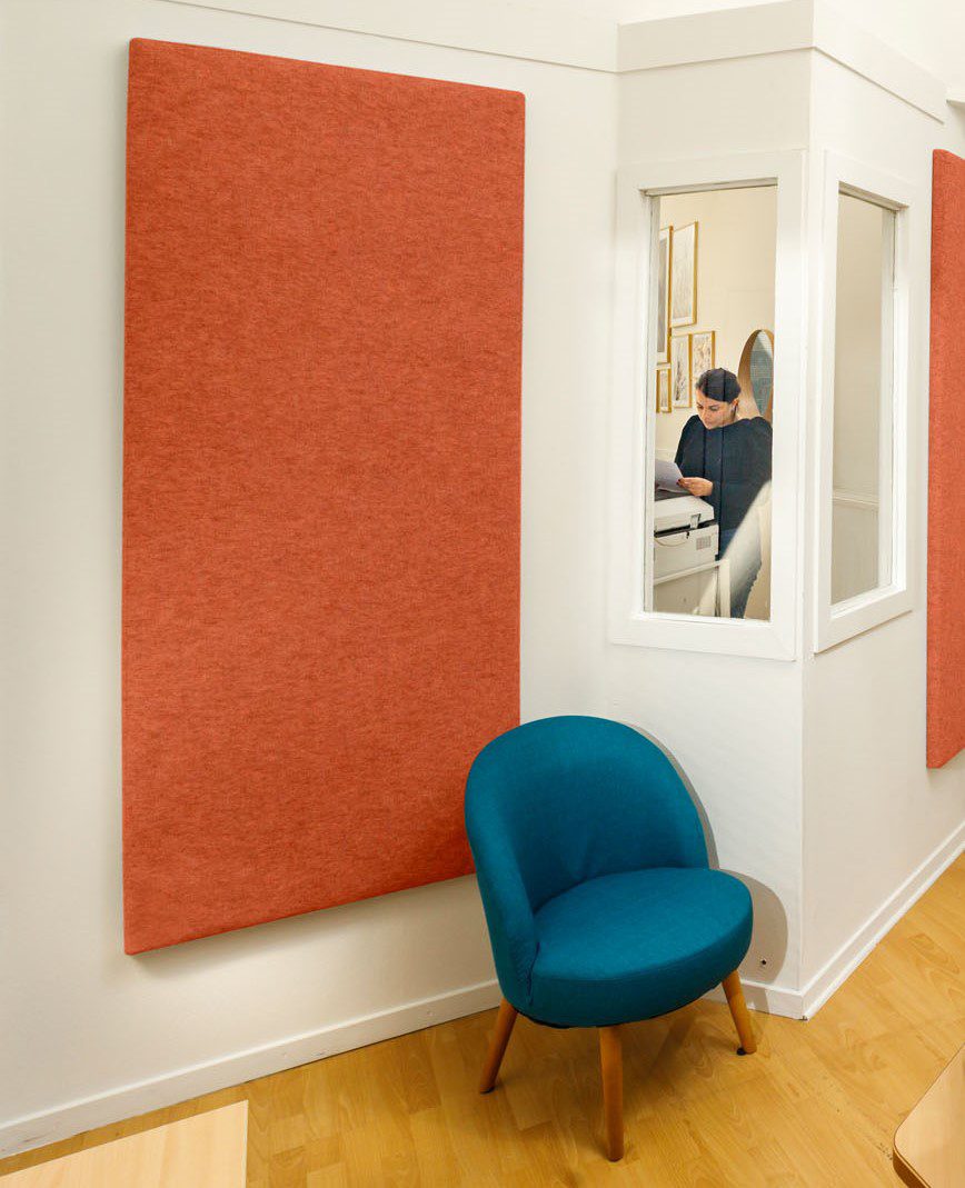 Akoestische wandpanelen in oranjetinten in een ruimte met zithoek