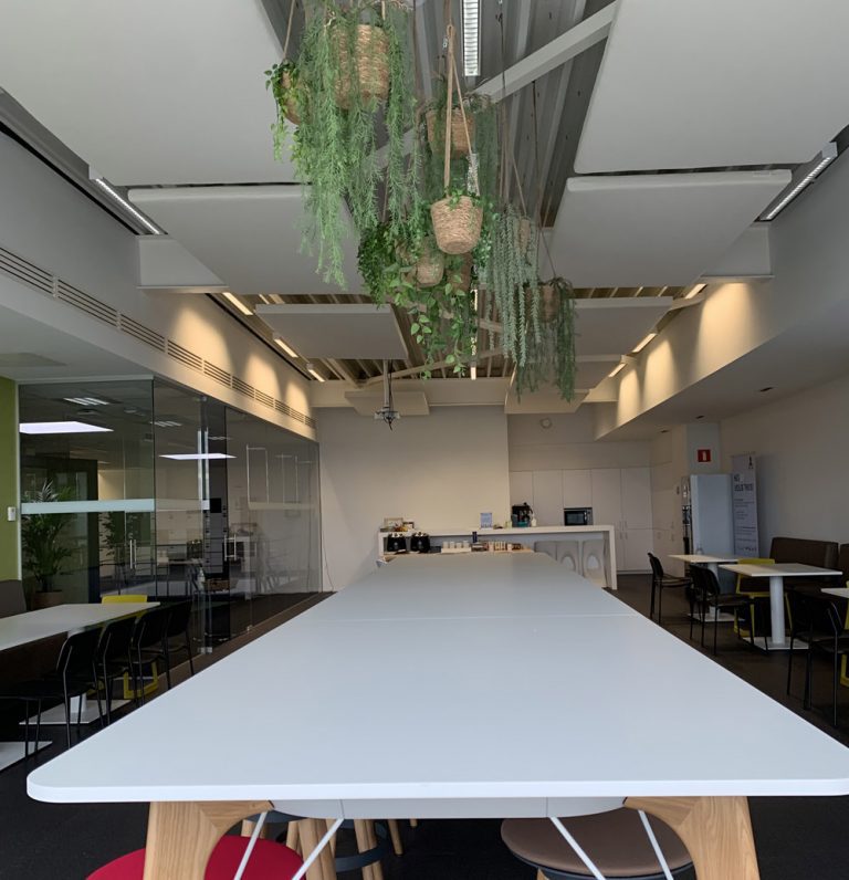 Groene akoestische plafondpanelen boven een vergadertafel