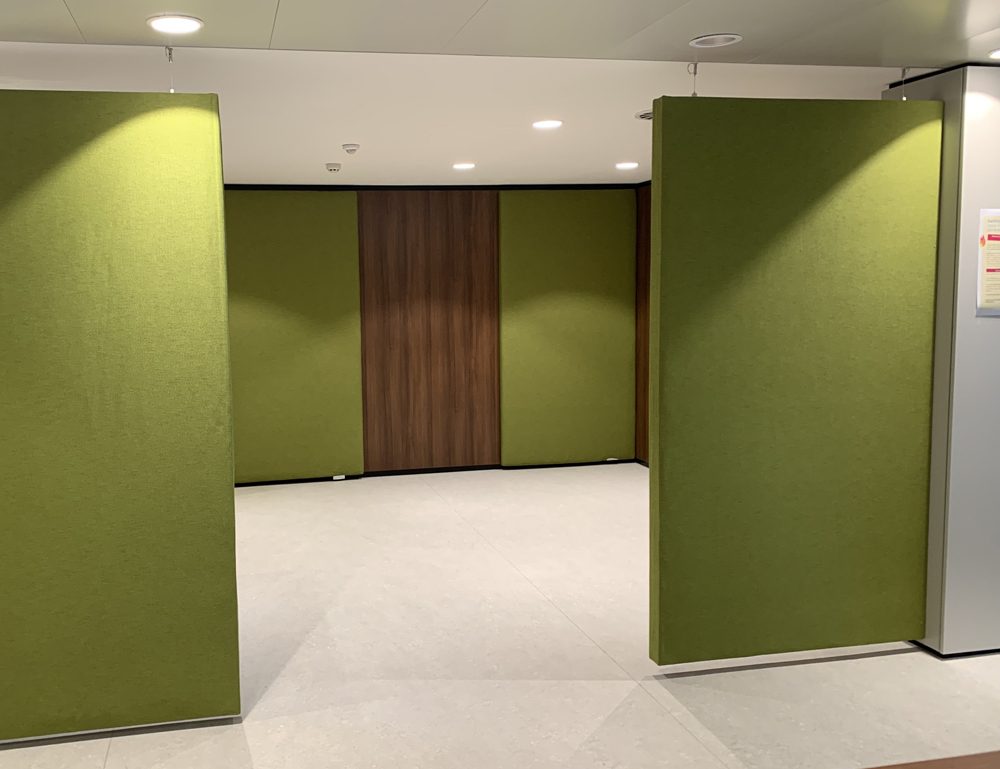 Groene akoestische wandpanelen in een doorgang van een kantoor