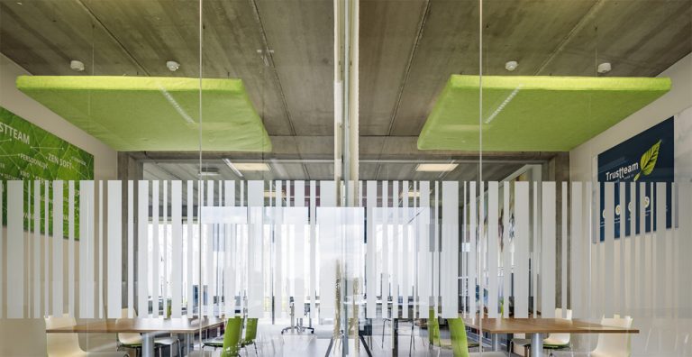 Groene akoestische plafondpanelen en verticale scheidingselementen in een kantoor