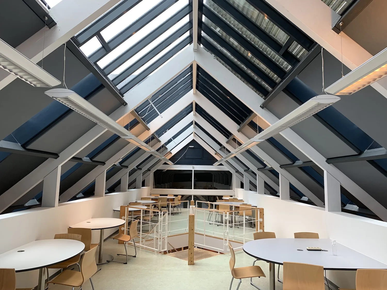 Akoestische plafondpanelen tussen de dakspanten in een loungeruimte