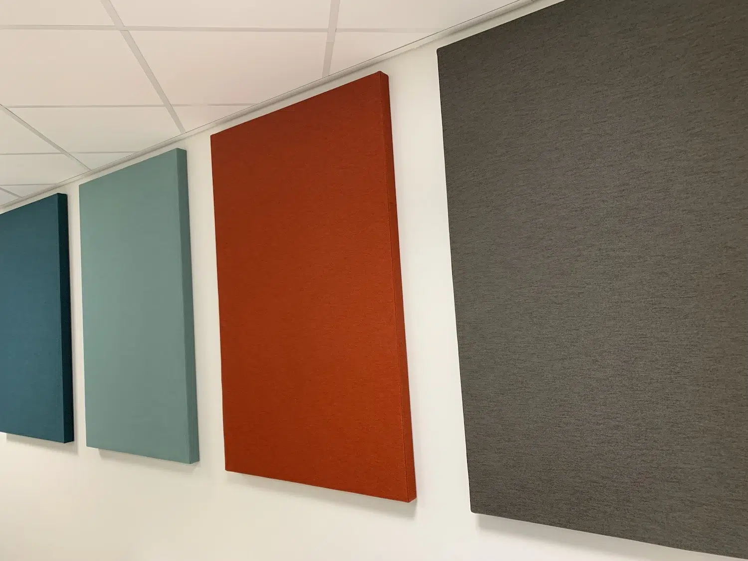 Kleurrijke akoestische wandpanelen in groenblauw, oranje en grijs